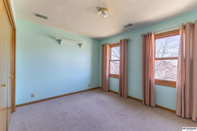 unfurnished room featuring light carpet, visible vents, and baseboards