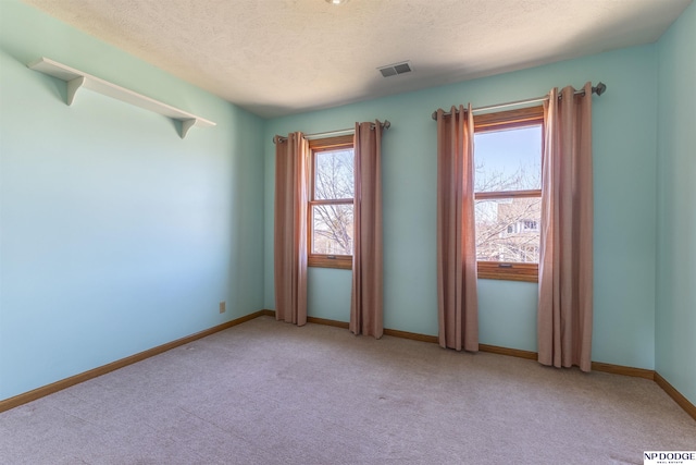 empty room with visible vents, light carpet, baseboards, and a textured ceiling