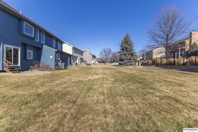 view of yard featuring entry steps, a residential view, and central air condition unit