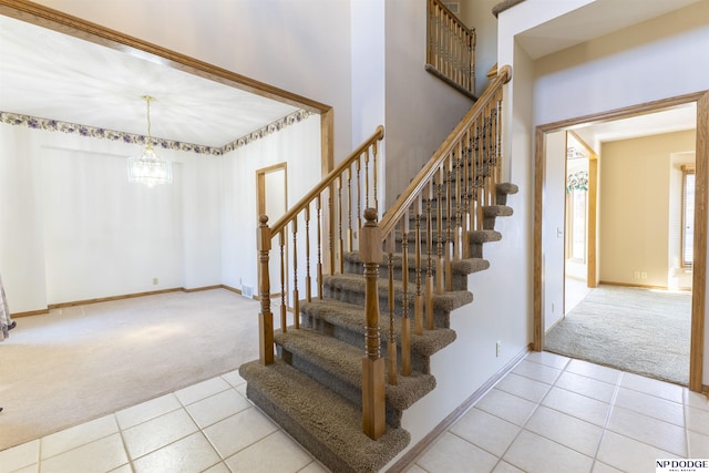 staircase with a chandelier, tile patterned flooring, carpet flooring, and baseboards