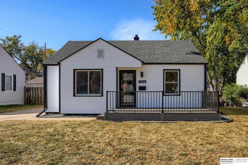 bungalow-style home featuring roof with shingles, fence, a chimney, and a front lawn