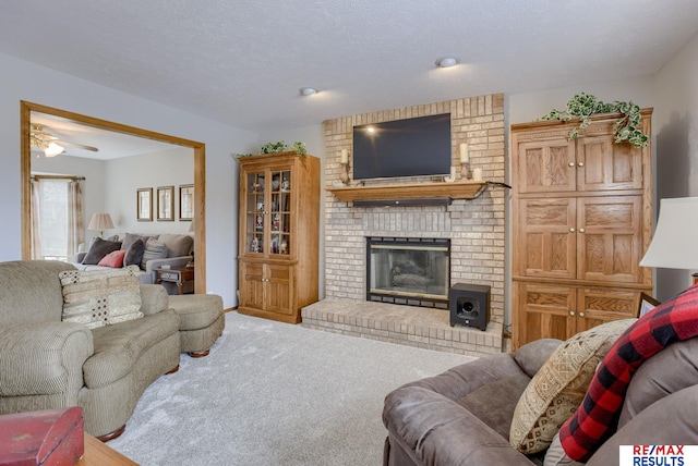 living area with a brick fireplace, a textured ceiling, and carpet flooring