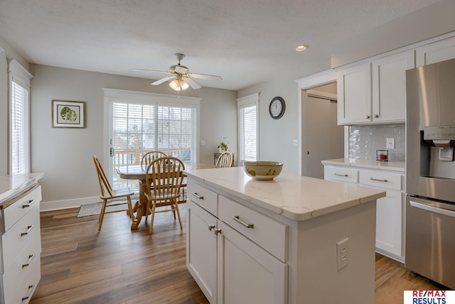 kitchen featuring a center island, backsplash, white cabinets, light wood-type flooring, and stainless steel fridge with ice dispenser