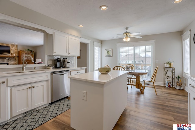 kitchen with a sink, a wealth of natural light, dishwasher, and wood finished floors