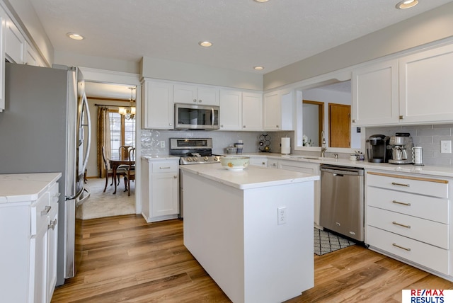 kitchen featuring stainless steel appliances, light wood finished floors, a sink, and white cabinetry