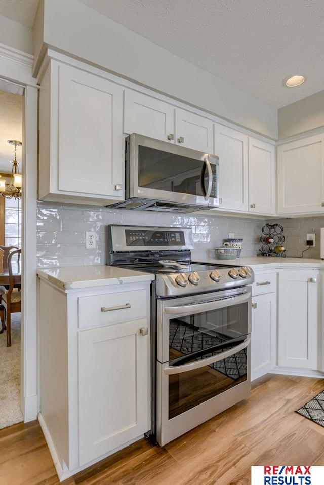 kitchen featuring white cabinets, light wood-style floors, appliances with stainless steel finishes, and light countertops