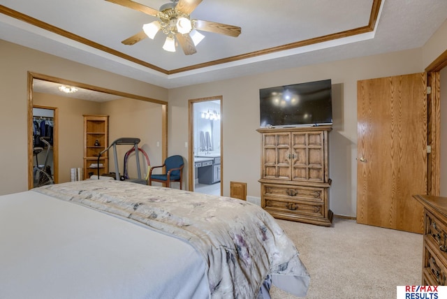 bedroom featuring ensuite bath, a raised ceiling, a ceiling fan, and light colored carpet