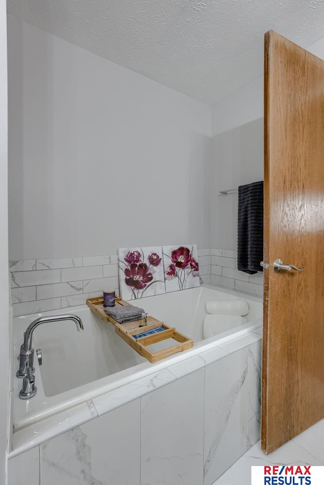 full bathroom with a garden tub and a textured ceiling