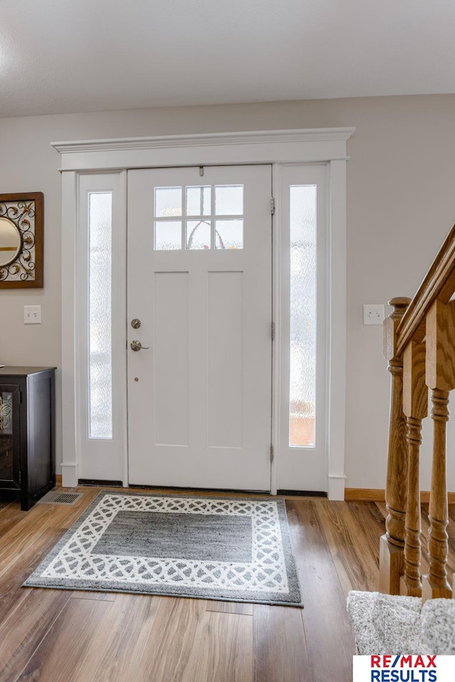 foyer entrance with light wood finished floors, stairway, plenty of natural light, and baseboards