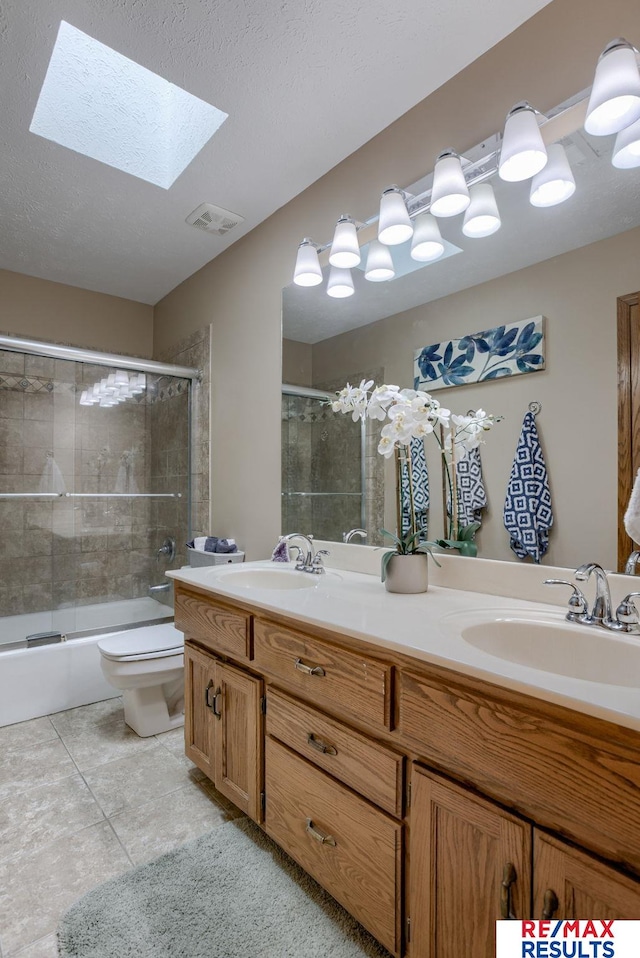 bathroom with a skylight, visible vents, a sink, and double vanity