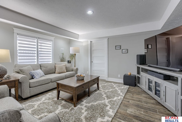 living room with a textured ceiling, baseboards, wood finished floors, and recessed lighting