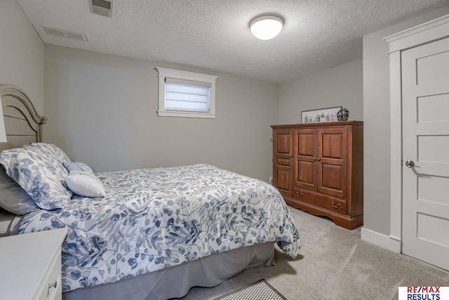 bedroom featuring light carpet, a textured ceiling, and visible vents