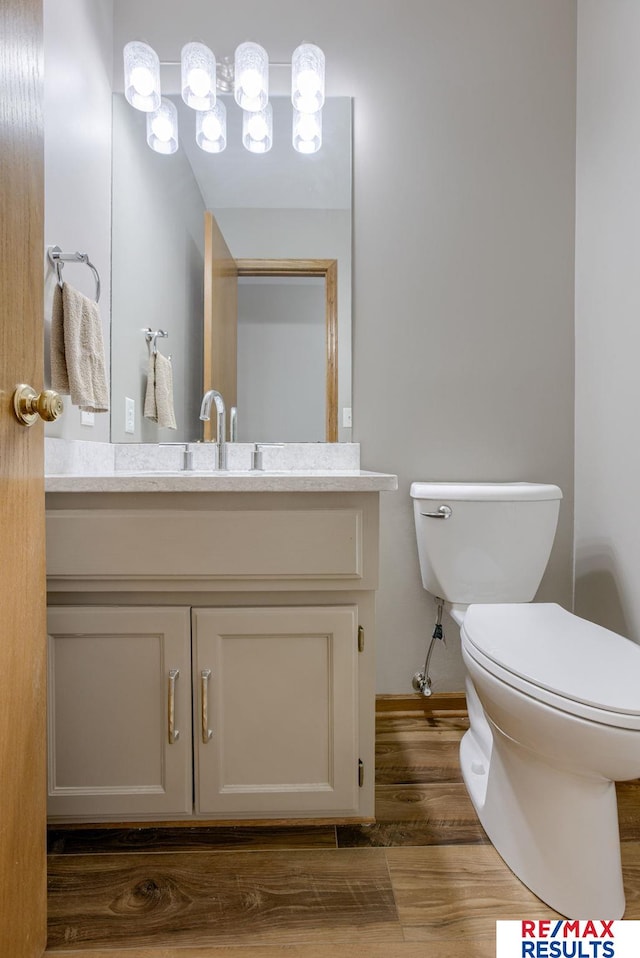 half bath featuring vanity, wood finished floors, and toilet