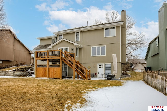 snow covered house with a patio, fence, stairs, a lawn, and a wooden deck