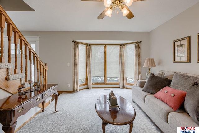 living area with light carpet, ceiling fan, stairway, and baseboards