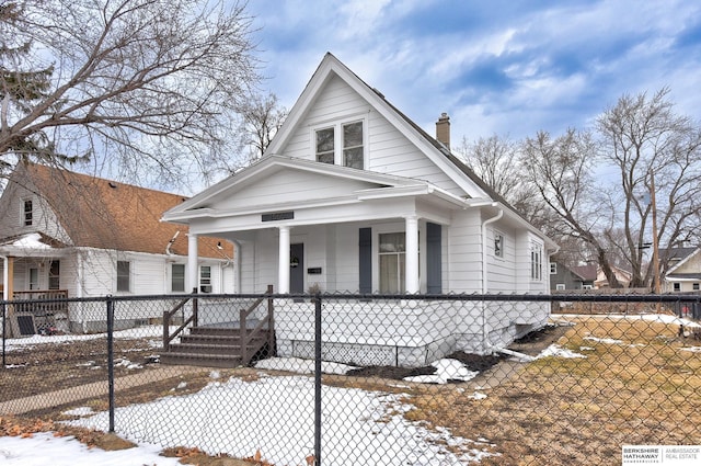 view of front of house with a porch, a fenced front yard, and a chimney