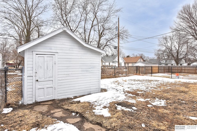 snow covered structure featuring a fenced backyard, an outdoor structure, and a storage unit