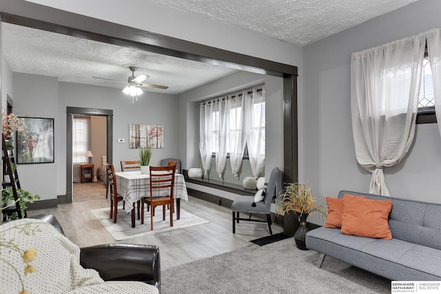 dining space with light wood-type flooring, ceiling fan, a textured ceiling, and baseboards