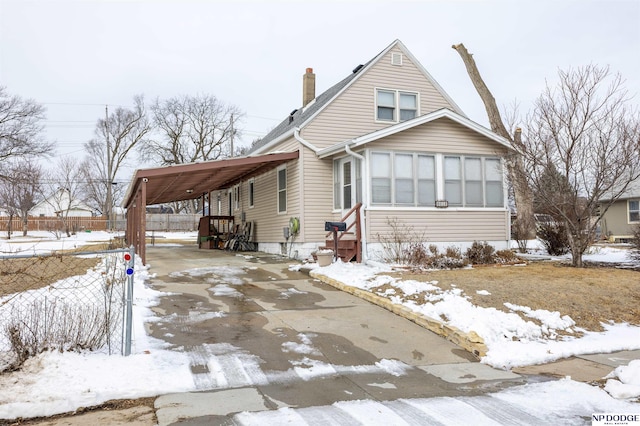 bungalow featuring entry steps, a carport, concrete driveway, and fence