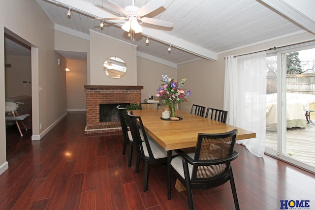 dining space featuring vaulted ceiling with beams, a brick fireplace, wood-type flooring, and track lighting