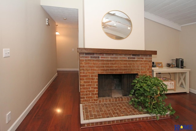 living room with a brick fireplace, baseboards, and wood finished floors