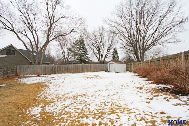 yard covered in snow with a shed, a fenced backyard, and an outdoor structure