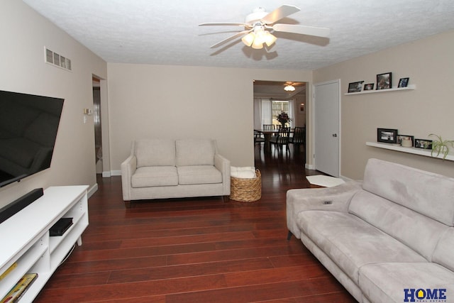 living room featuring a ceiling fan, visible vents, a textured ceiling, and wood finished floors