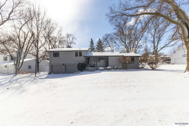 snow covered rear of property featuring a garage