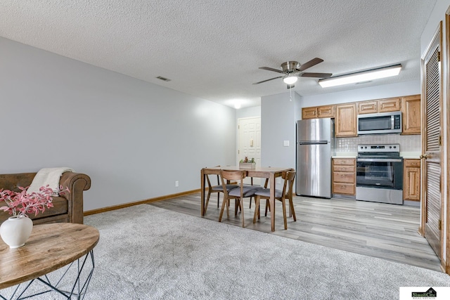 kitchen featuring light wood finished floors, visible vents, stainless steel appliances, light countertops, and backsplash