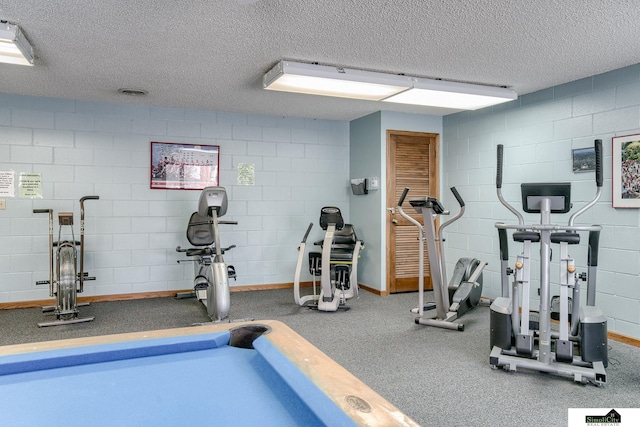 exercise room with a textured ceiling and concrete block wall