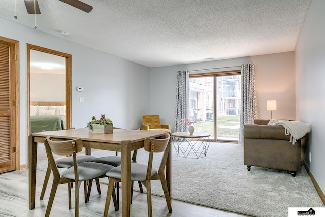 dining room with light wood-style flooring, a textured ceiling, baseboards, and a ceiling fan