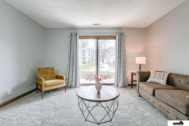 carpeted living room featuring baseboards, visible vents, and a textured ceiling