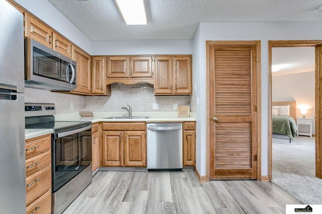 kitchen with stainless steel appliances, light countertops, a sink, and backsplash