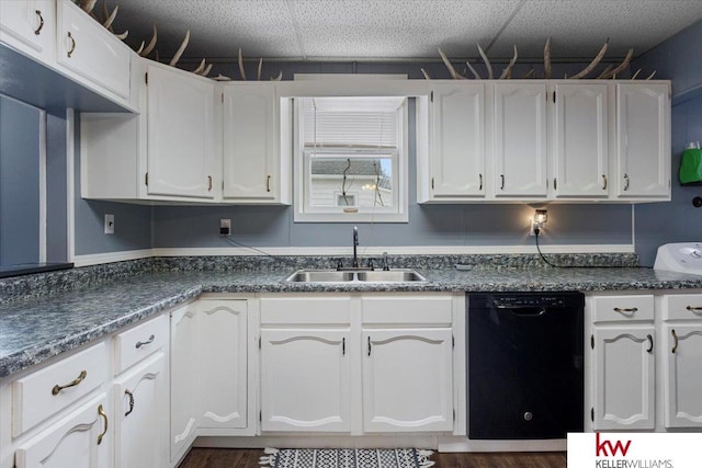 kitchen featuring dark countertops, black dishwasher, white cabinets, and a sink