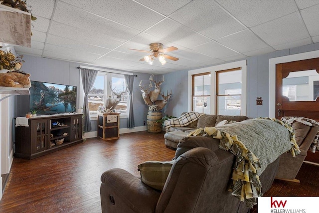 living room featuring ceiling fan, a drop ceiling, and wood finished floors