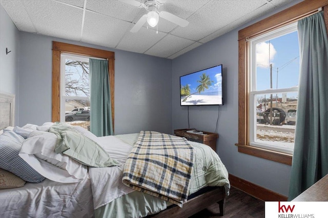 bedroom featuring a paneled ceiling, ceiling fan, baseboards, and wood finished floors