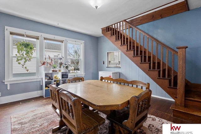 dining room with baseboards, stairs, visible vents, and wood finished floors