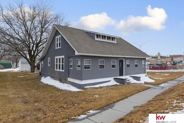 view of front facade featuring a shingled roof and a lawn