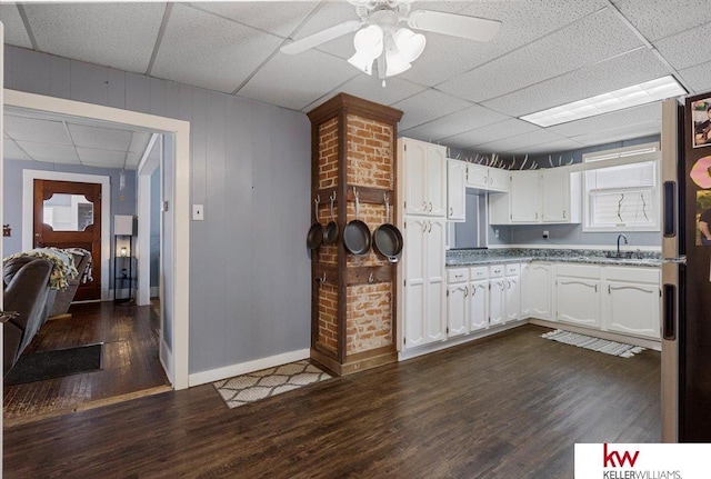 kitchen with white cabinets, a ceiling fan, dark wood-type flooring, a paneled ceiling, and a sink