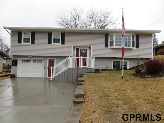 split foyer home featuring a front lawn, concrete driveway, and an attached garage