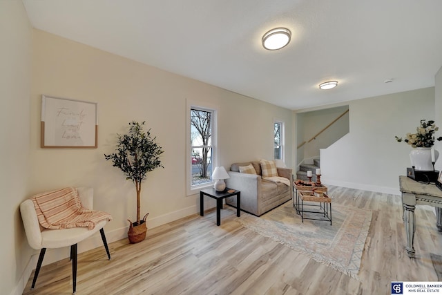 living room featuring light wood-style floors, stairs, and baseboards