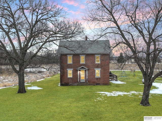 view of front facade with brick siding and a front lawn