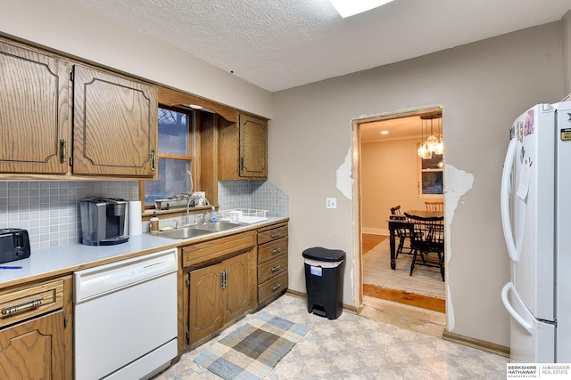 kitchen with white appliances, tasteful backsplash, light countertops, a textured ceiling, and a sink