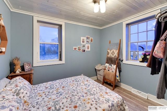 bedroom with baseboards, visible vents, wood ceiling, wood finished floors, and crown molding