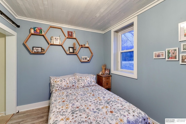 bedroom with a barn door, baseboards, wooden ceiling, ornamental molding, and wood finished floors