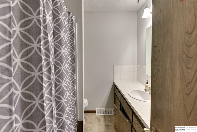 bathroom featuring a textured ceiling, toilet, visible vents, vanity, and tasteful backsplash