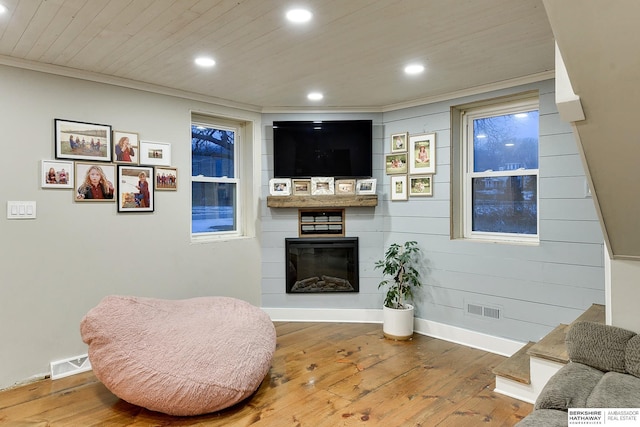 sitting room featuring wood ceiling, visible vents, wood-type flooring, and a glass covered fireplace