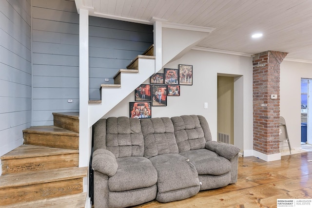 living area with wood finished floors, visible vents, crown molding, and stairs