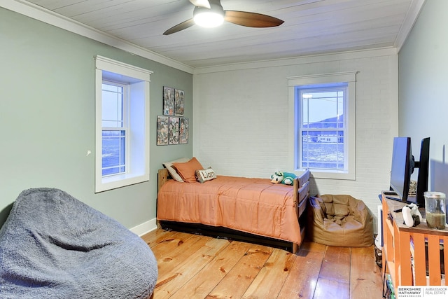 bedroom featuring ceiling fan, brick wall, hardwood / wood-style floors, and crown molding