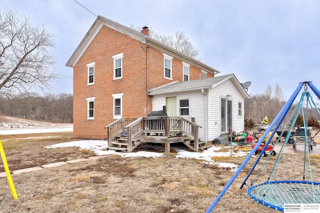 rear view of property with brick siding, a chimney, and a wooden deck